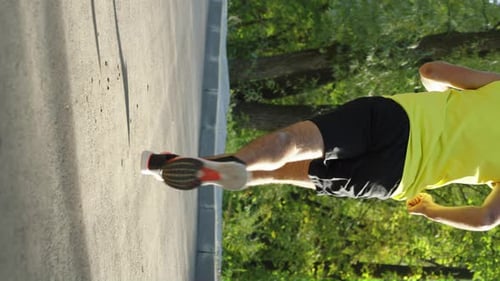 Vertical Screen Low Shot of Jogger on Road in Park