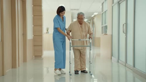 Elderly Man Uses Walker With Nurse in Hospital