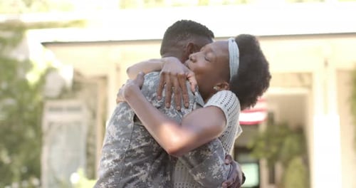Woman Embraces Military Man in Front of House