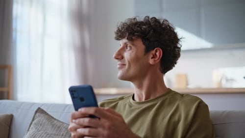 Man Using Smartphone Sitting on Couch Indoors