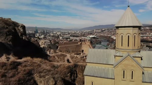 Aerial cityscape of Tbilisi with Mtkwari river, Narikala fortress and Caucasus mountains in Georgia