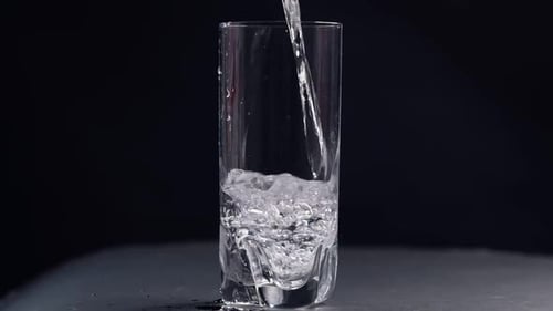 Studio Shoot of Water Pouring Into Transparent Glass on Black Background Slow Motion Video Close Up