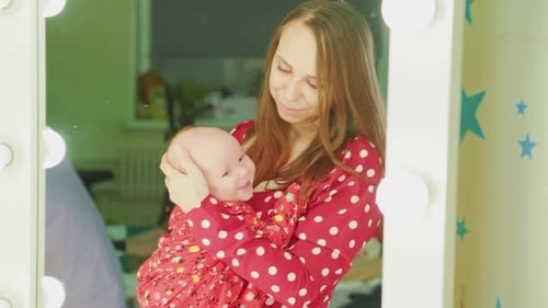 Woman holding infant near mirror inside home