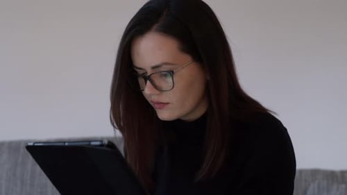 Woman Using Tablet Device Relaxing on Couch Indoors