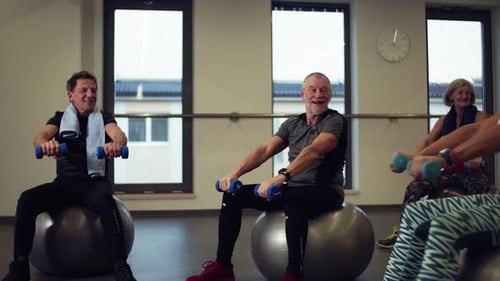 Cheerful seniors enjoy active lifestyle with dumbbell exercise in gym session