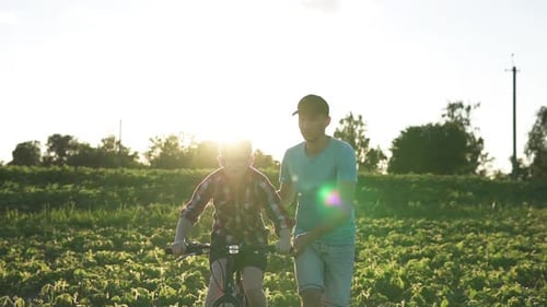 A Happy Family Father Teaches His Son to Ride a Bike in the Park