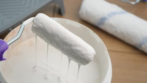 Fresh Paint Roller Dripping Above the Paint Bucket