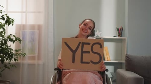 Woman in Wheelchair Holds Sign Saying Yes