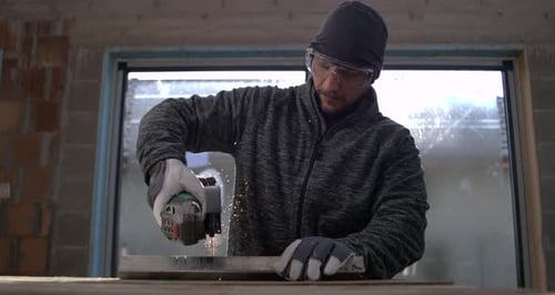 Man Using Angle Grinder Cutting Metal Indoors
