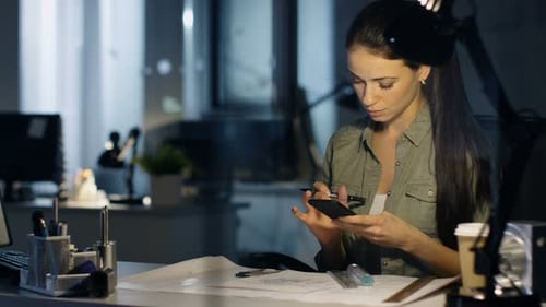 Late at Night Female Design Engineer Works on Drafts, She Uses Smartphone and Makes Corrections on
