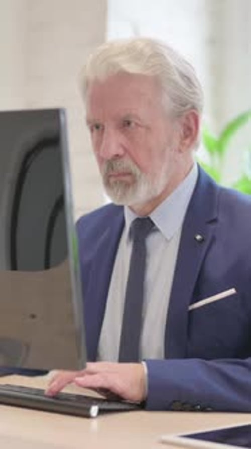 Senior Businessman Typing on Computer in Office Setting