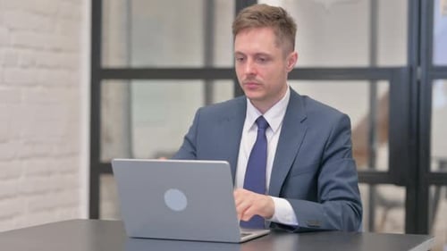 Young Businessman Leaving Office after Working on Laptop