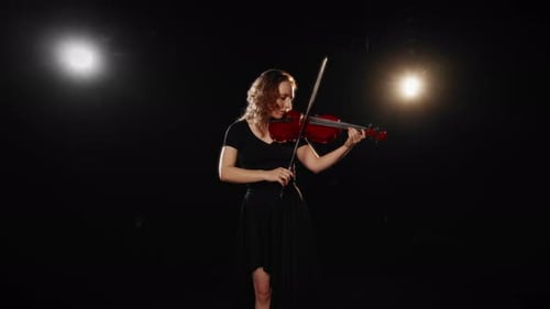 Woman Playing Violin in a Dark Room