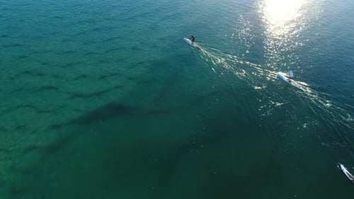 Aerial view of Paddle boarders out enjoying the calm flat crystal clear water on a beautiful morning