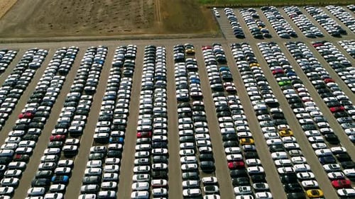 Aerial footage of finished cars ready to be shipped on huge distribution center