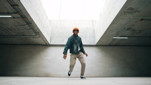 Stylish happy hipster perform break dance or foot step in building. Sprightly.