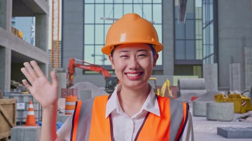 Asian Female Engineer Smiling To Camera And Waving Hand Saying Bye at Construction Site