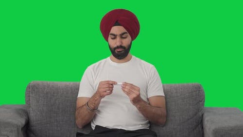 Sick Sikh Indian man using thermometer to check fever Green screen