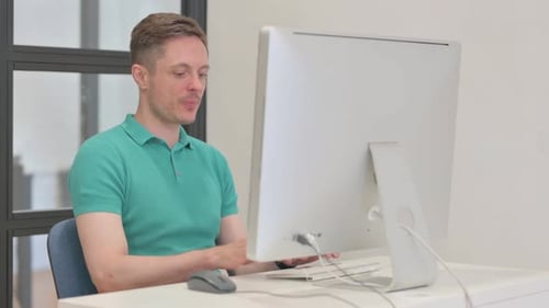 Man Celebrates Good News at Computer in Office