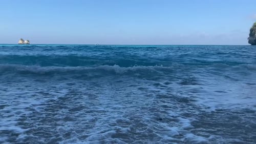 Nahaufnahme von türkisblauen Wellen, die an Land gespült werden, herabstürzende Felsen mit weißem Sandstrand in Diamond