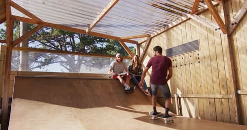 Video of happy diverse female and male skateboarders training in skate park