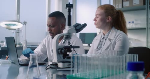 Scientists Analyzing Microscope Data in Bright Laboratory