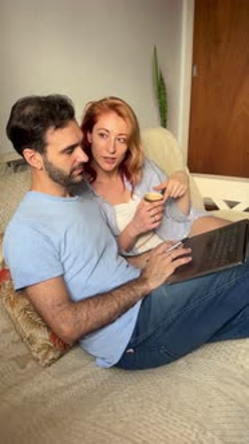 Couple relaxing at home looking at a laptop