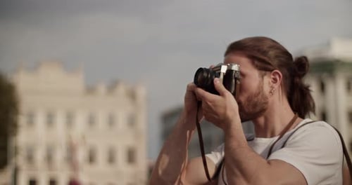 Young Man Photographs with Camera in the City