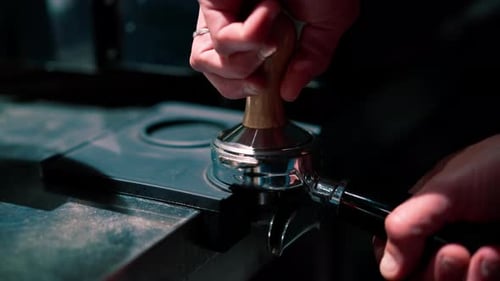 close-up of a barista's hand pressing freshly ground coffee before preparing it in a coffee machine