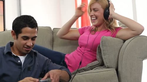 Couple relaxing on couch indoors listening to music