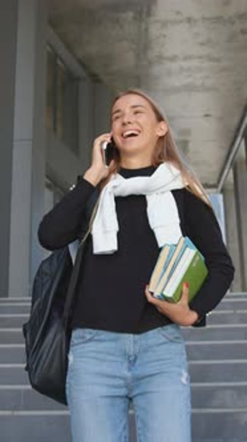 Smiling Woman with Books Talking on Smartphone on Steps