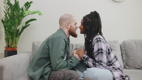 Loving Couple Holding Hands and Kissing on Sofa