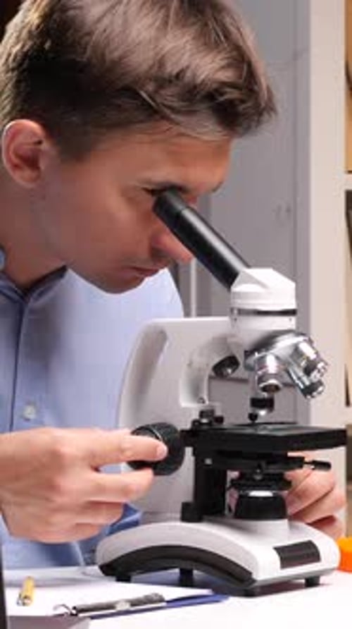 Vertical Video Scientist Working with Microscope Doing Research in Laboratory at Night