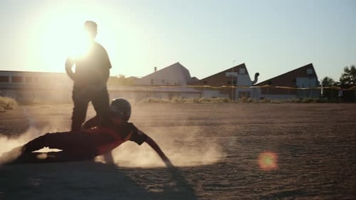 Baseball player sliding into a base at sunset