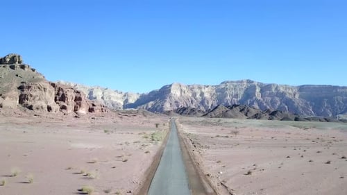 Empty desert road with mountains and blue sky in the background