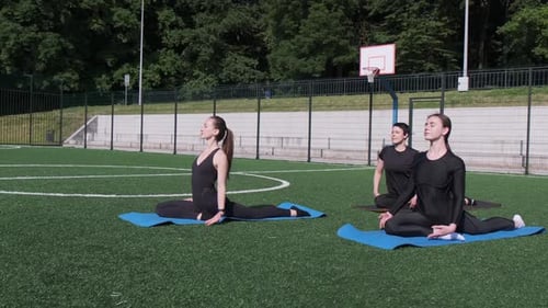 Women practicing yoga stretches on the grass outdoors