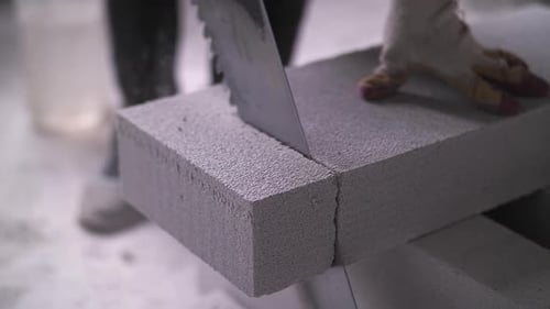Worker Sawing White Building Blocks
