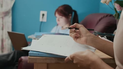 Close-up of Unknown Student Working on Her Math Homework at Wooden Table