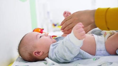 Loving Mother Changing Baby on Changing Table