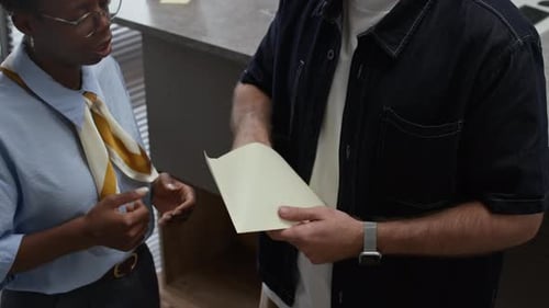 Client Taking Card out of Envelope Talking to Female Bank Manager in Office