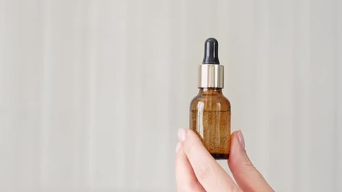 Woman Holds Amber Glass Bottle with Dropper