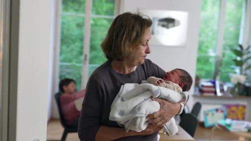Woman Holding Newborn Baby with Child in Background
