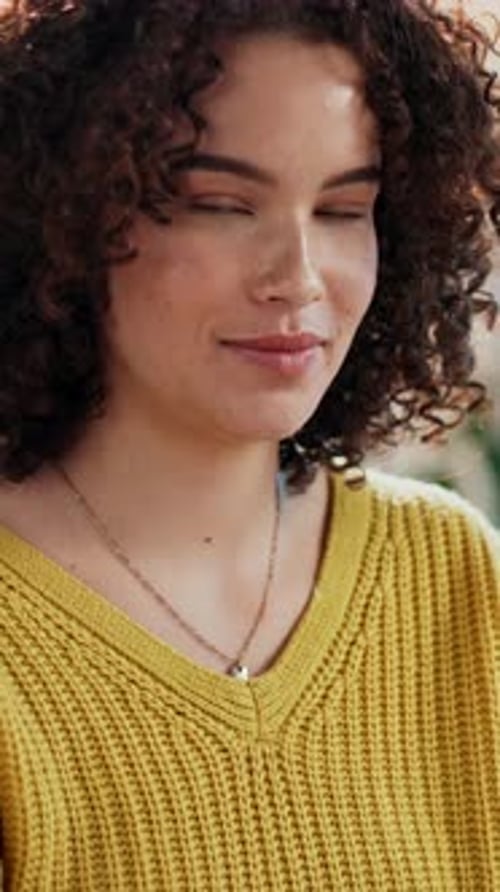 Smiling woman with curly hair in bright sweater