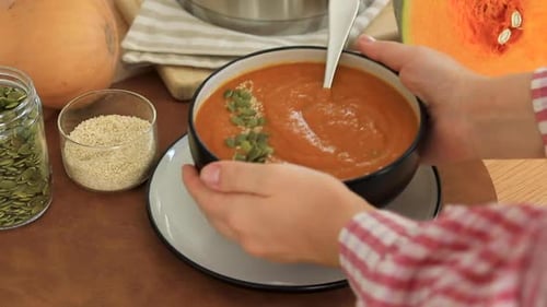 A Woman Puts a Plate of Pumpkin Soup on the Table Autumn Menu Video