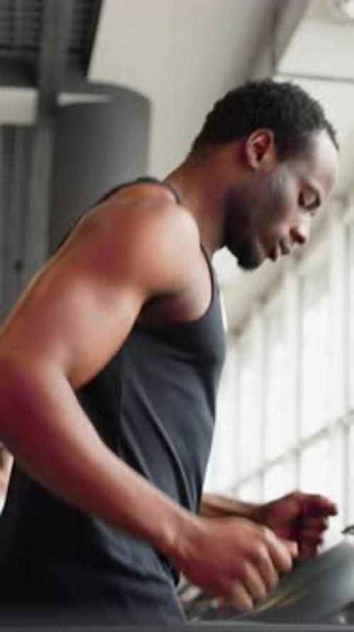 Young African Man in Sportswear Running on Treadmill at Gym Vertical Video