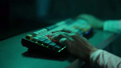 Ausgeschnittene Aufnahme einer nicht wiederzuerkennenden Hackerin, die auf einer drahtlosen mechanischen RGB-Tastatur tippt, mit