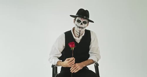 Stylish Man with Skeleton Face Paint Holding Rose