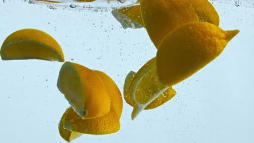 Fresh Orange Wedges Submerged Under Transparent Water in Super Close