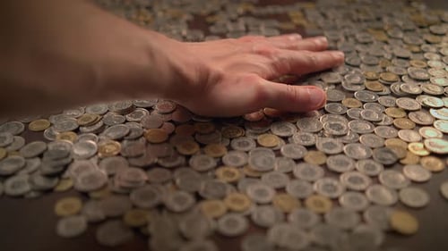 Hand Moving Across Scattered Coins