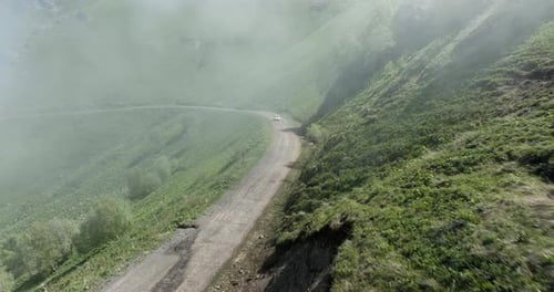 Car Driving On Dirt Road Of Tskhratskaro Pass Passing Through Fog On A Sunny Day In Georgia. - aeria